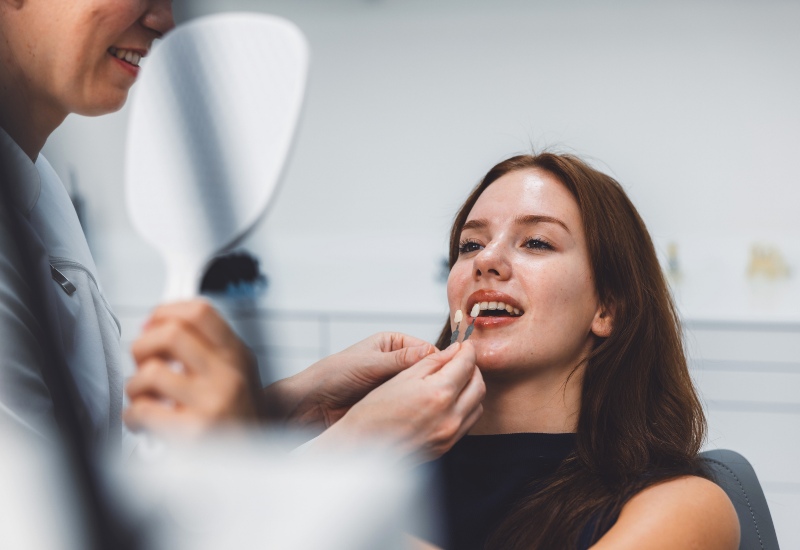 A dentist performing shade matching for a veneer on a patient during consultation in Germantown, TN